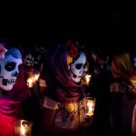 Merida Mexico Three women with Catrina costumes and skull make-up holding candels at the parade for dia de los muertos at the Festival Des Las Animas