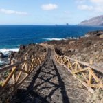Pathway along the ocean through black lava rocks to natural pool Charco de los Sargos, El Golfo, El Hierro, Canary Islands, Spain