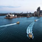Cityscape of Sydney with Opera house and ferry boats in the blue ocean after sunset, Australia
