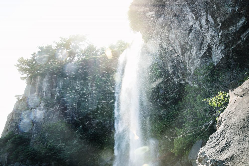 Water of the Joengbang waterfall splashing from the cliffs at Jeju Island, South Korea