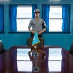 JSA within DMZ Korea UN soldier at table with UN flag in blue building at North South Korean border at Korean Demilitarized Zone, Panmunjom