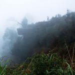 Kodaikanal, India - Man walking on rock formation called 'dolphins nose' in thick fog