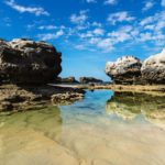Three rock formations with reflections in the sea at Peterborough beach, Victoria, Australia