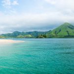 Indonesia, Volcanic mountain coastline of Flores with green hills along the turquoise ocean and sandy beac