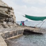 Local women selling fresh seafood sitting under a cover at the cliffs along the ocean at Yongmeori Beach, Sanbang-ro, Jeju Island, South Korea
